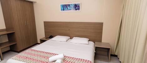 Ein Hotelzimmer mit Bett, Nachttisch, Schrank und einem Bild an der Wand.