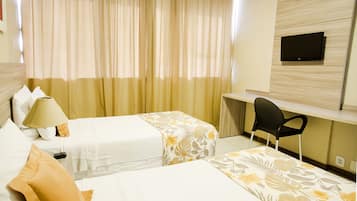 Habitación de hotel con dos camas, un escritorio, una silla, un televisor y una lámpara.