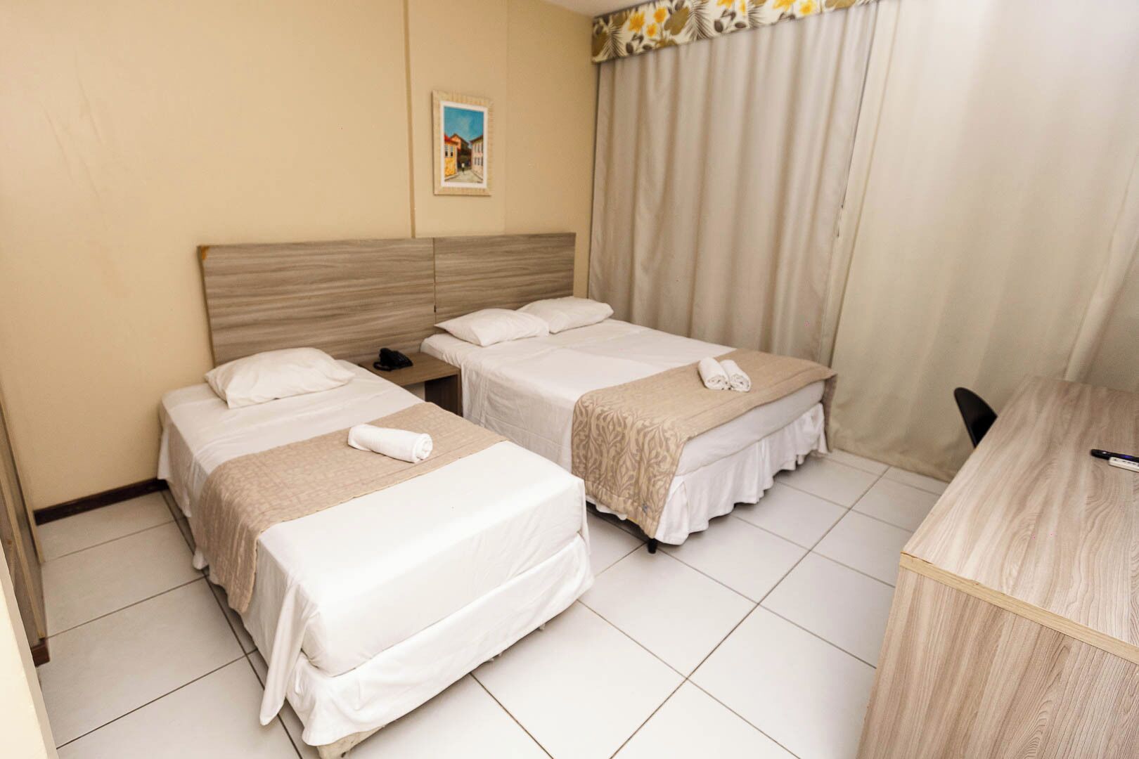 Une chambre d’hôtel avec deux lits simples, un bureau et une chaise.