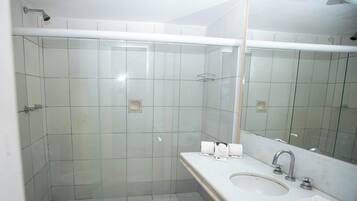 Un baño moderno con cabina de ducha de vidrio, lavamanos con espejo e inodoro.