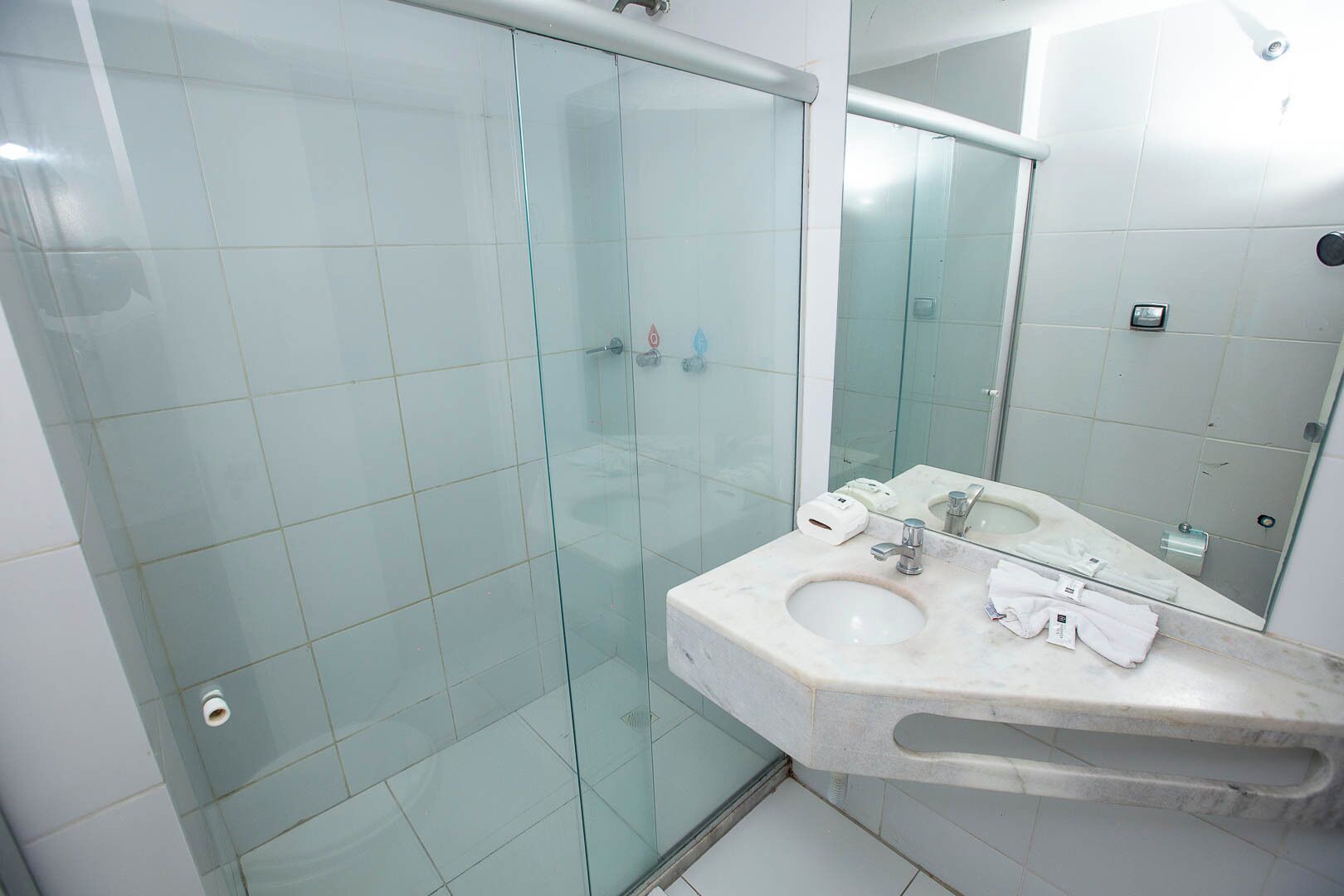 A bathroom with a glass-enclosed shower, a marble sink, and a large mirror.