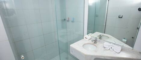 Une salle de bain dotée d’une douche à parois de verre, d’un lavabo en marbre et d’un grand miroir.