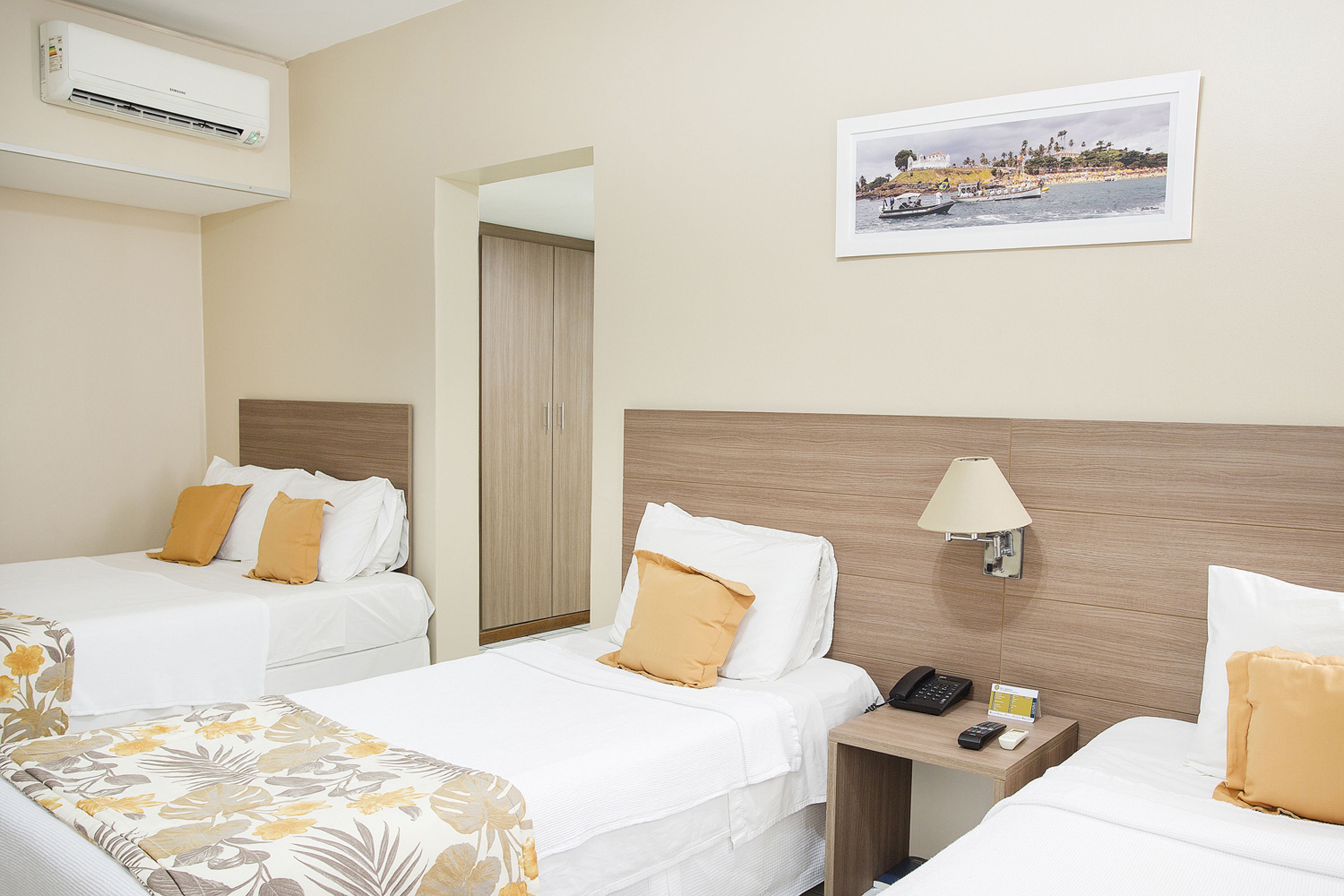 Ein Hotelzimmer mit zwei Betten, einem Nachttisch, einer Lampe, einem Telefon und einem gerahmten Bild an der Wand.