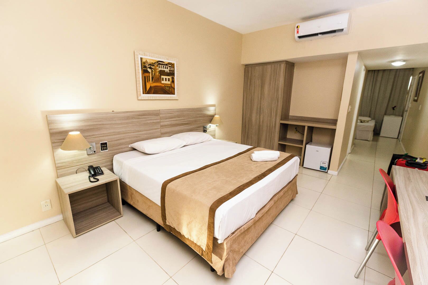A hotel room with a large bed, bedside tables, a desk, and a chair.
