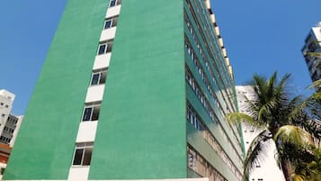 Un edificio alto con fachada verde y varias ventanas.