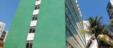 Un immeuble de grande hauteur, doté d’une façade verte et de nombreuses fenêtres.