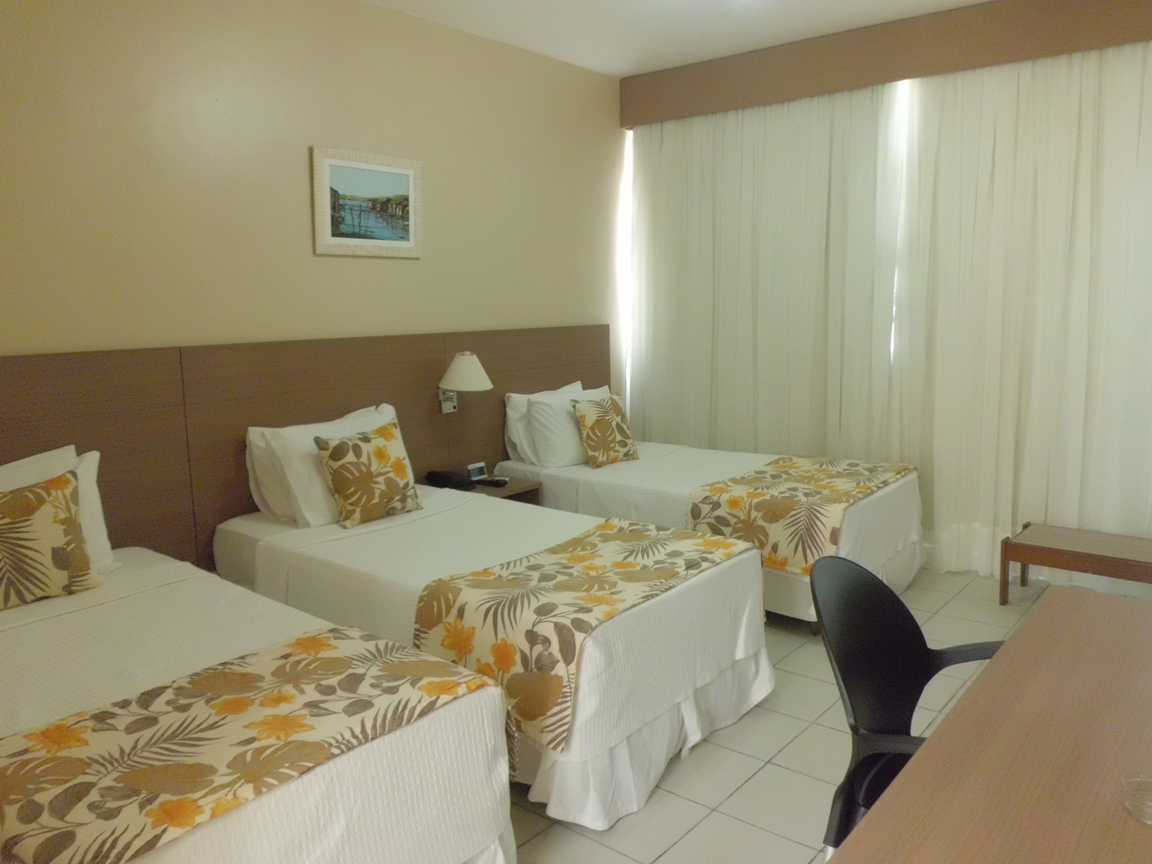 A hotel room with two single beds, a desk, and a chair.