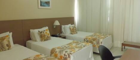 A hotel room with two single beds, a desk, and a chair.