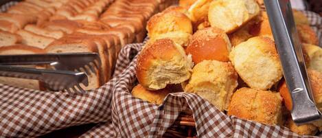A variety of baked goods, including bread and rolls, arranged on a table with checkered cloths.