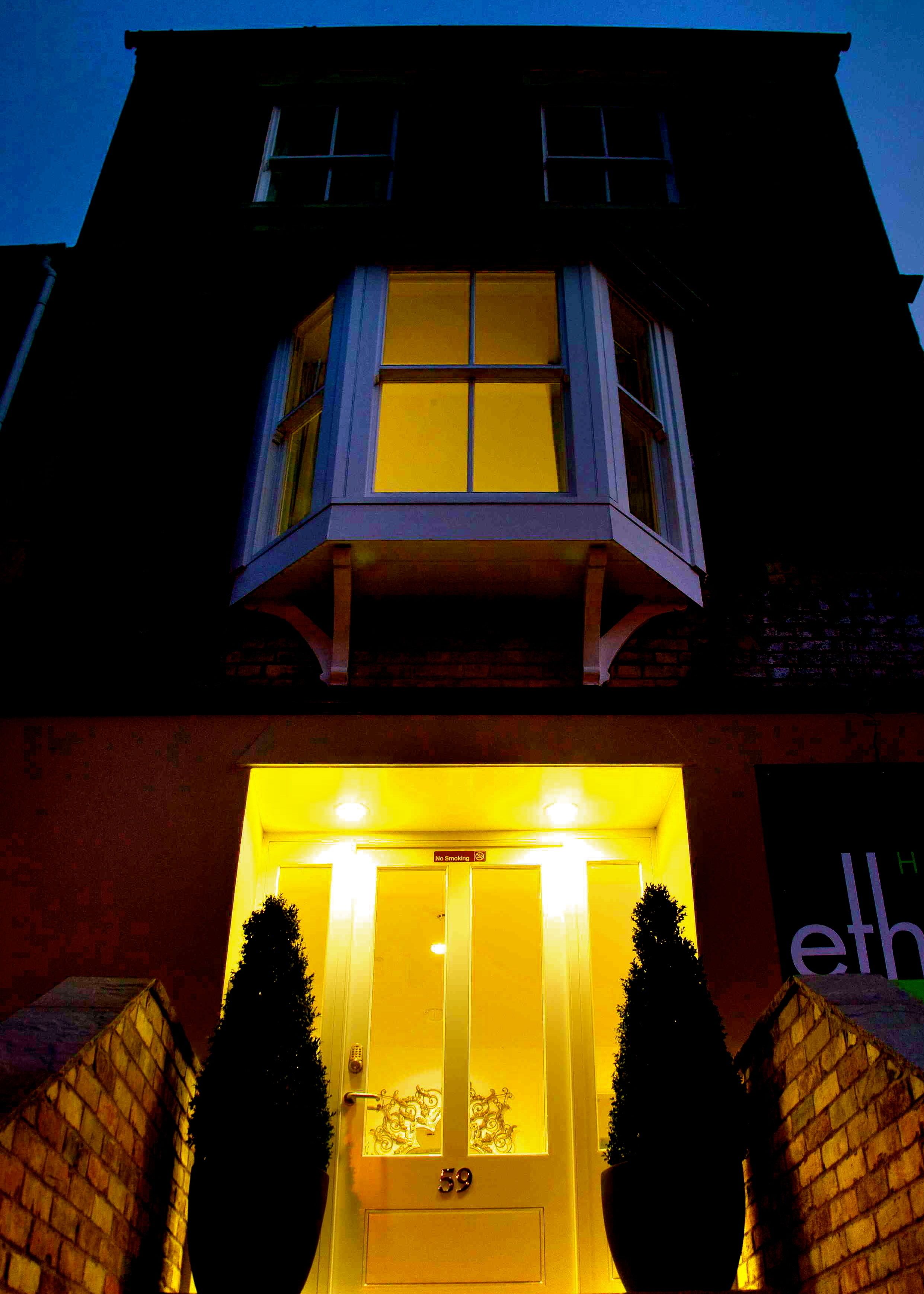 A building with a prominent bay window and a lit entrance.