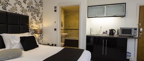A hotel room with a bed, a desk, a microwave, and a bathroom visible through an open door.