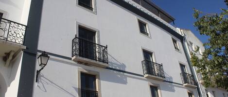 A multi-story building with balconies, a sign reading "RE/MAX", and a street lamp.