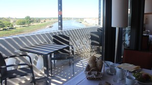 A balcony with a table set for breakfast, overlooking a river. - Hotel Ordem de Santiago (Alcacer do Sal)