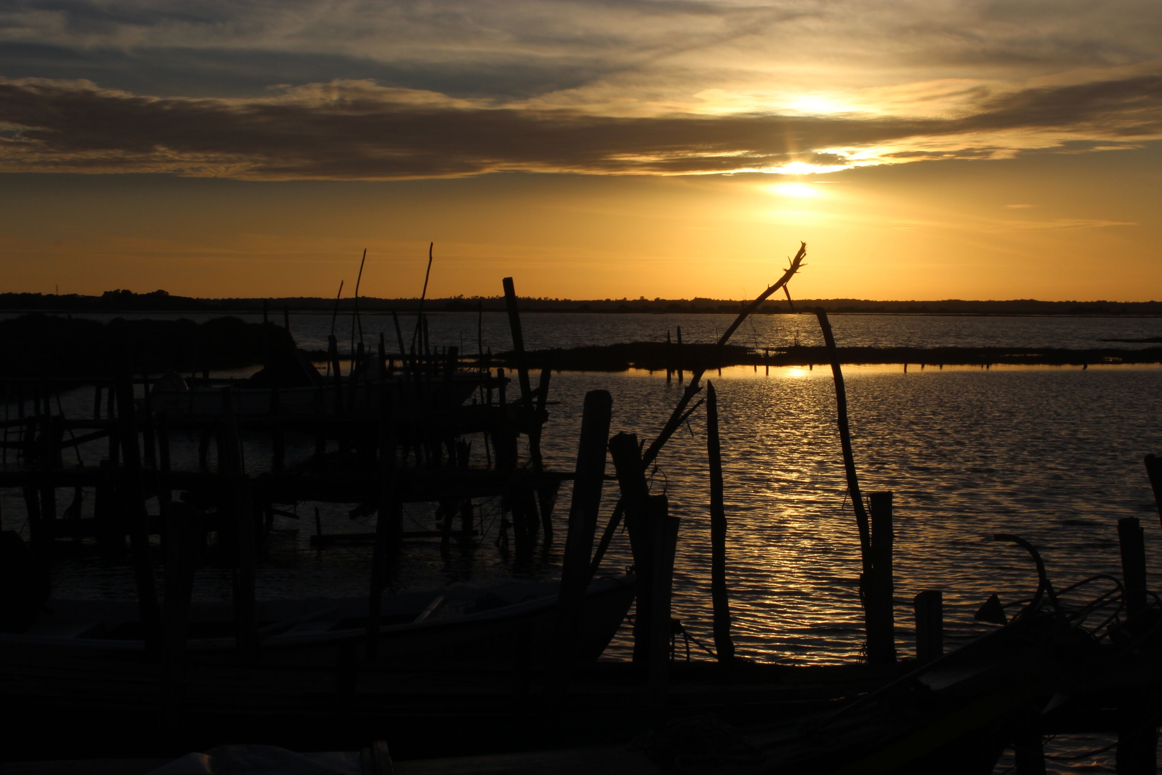 A sunset over a calm body of water with wooden structures in the foreground.