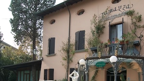 A courtyard with a fountain, potted plants, and a building with a sign reading "Panazza." - Panazza Hotel (Mordano)