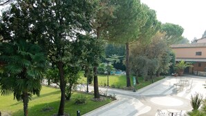 A courtyard with a paved walkway, outdoor seating, and trees. - Panazza Hotel (Mordano)