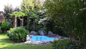 A garden with a swimming pool, a statue, and various plants. - Panazza Hotel (Mordano)