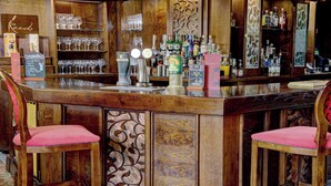 A bar area with a wooden counter, bar stools, and various bottles and glasses. - Pastures Hotel (Doncaster)