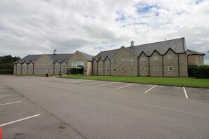 A large, multi-story building with a symmetrical facade, a central entrance, and a parking lot in front. - Pastures Hotel (Doncaster)
