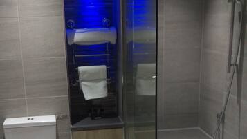 A modern bathroom with a toilet, a glass-enclosed shower, and a blue-lit wall.