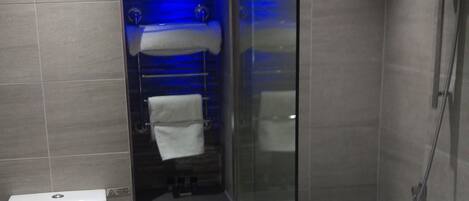 Un bagno moderno con il water, una cabina doccia in vetro e una parete illuminata di blu.