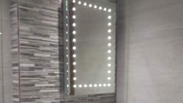 Un bagno moderno con un lavabo rettangolare, uno specchio con luci a LED e una parete strutturata.