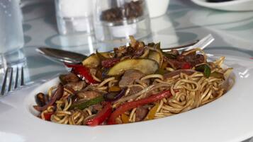 Un plato de fideos salteados con verduras y carne.