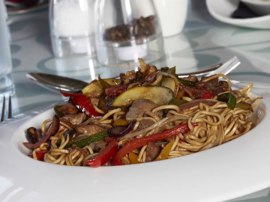 Un plato de fideos salteados con verduras y carne.