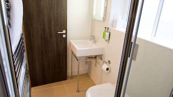 Une salle de bain avec des toilettes, un lavabo et une douche.