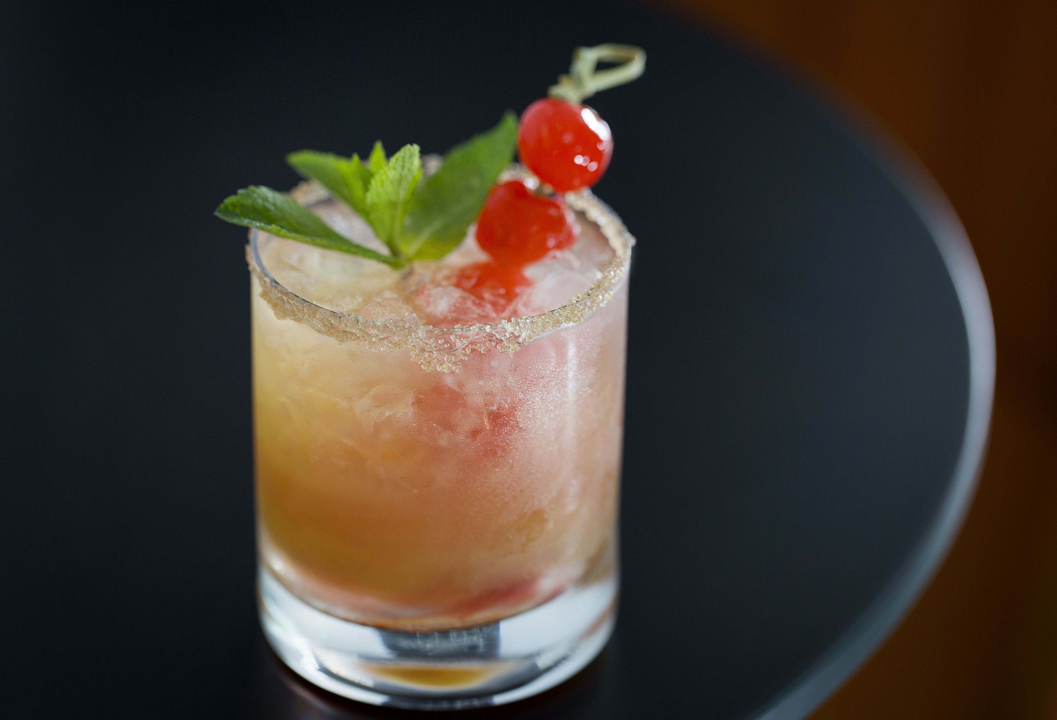 Un cocktail servi dans un verre, avec des glaçons et une garniture.