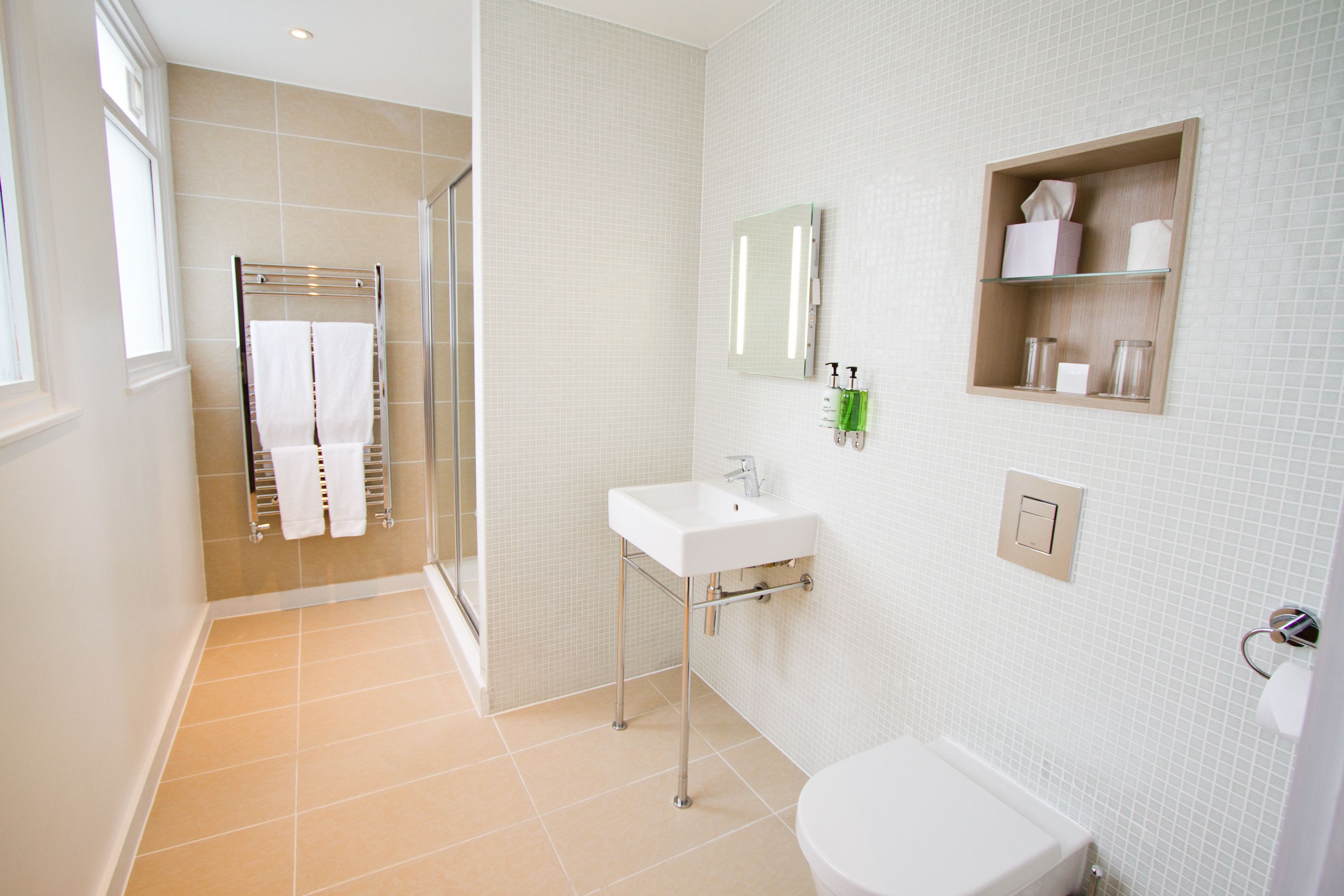 Un baño moderno con cabina de ducha de vidrio, un lavabo blanco y un inodoro.