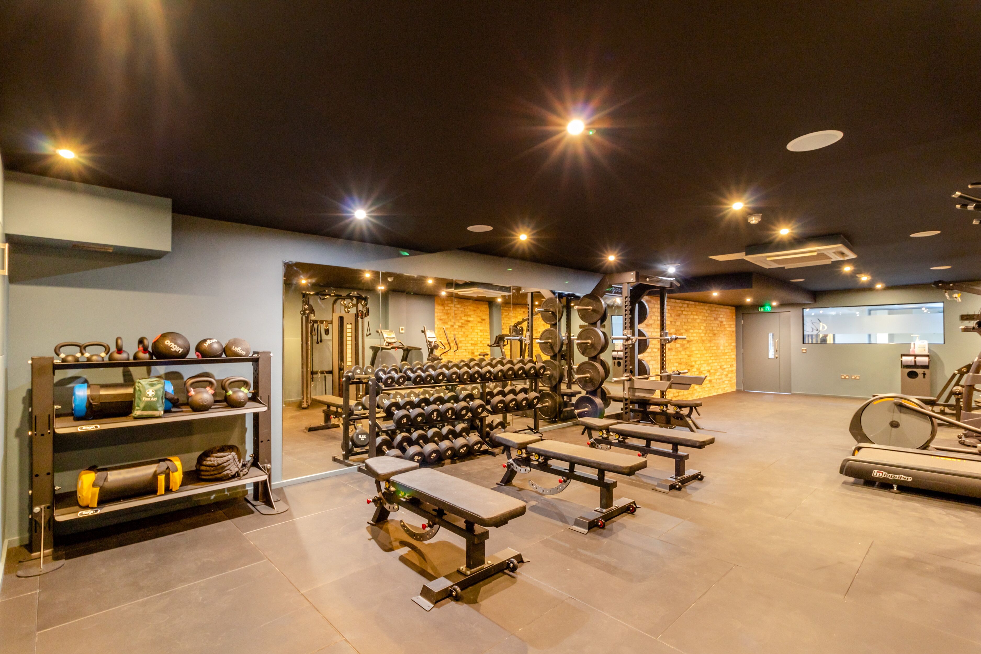 A gym with weightlifting equipment, benches, and cardio machines.