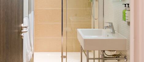 A modern bathroom with a glass-enclosed shower, a white sink, and a toilet.