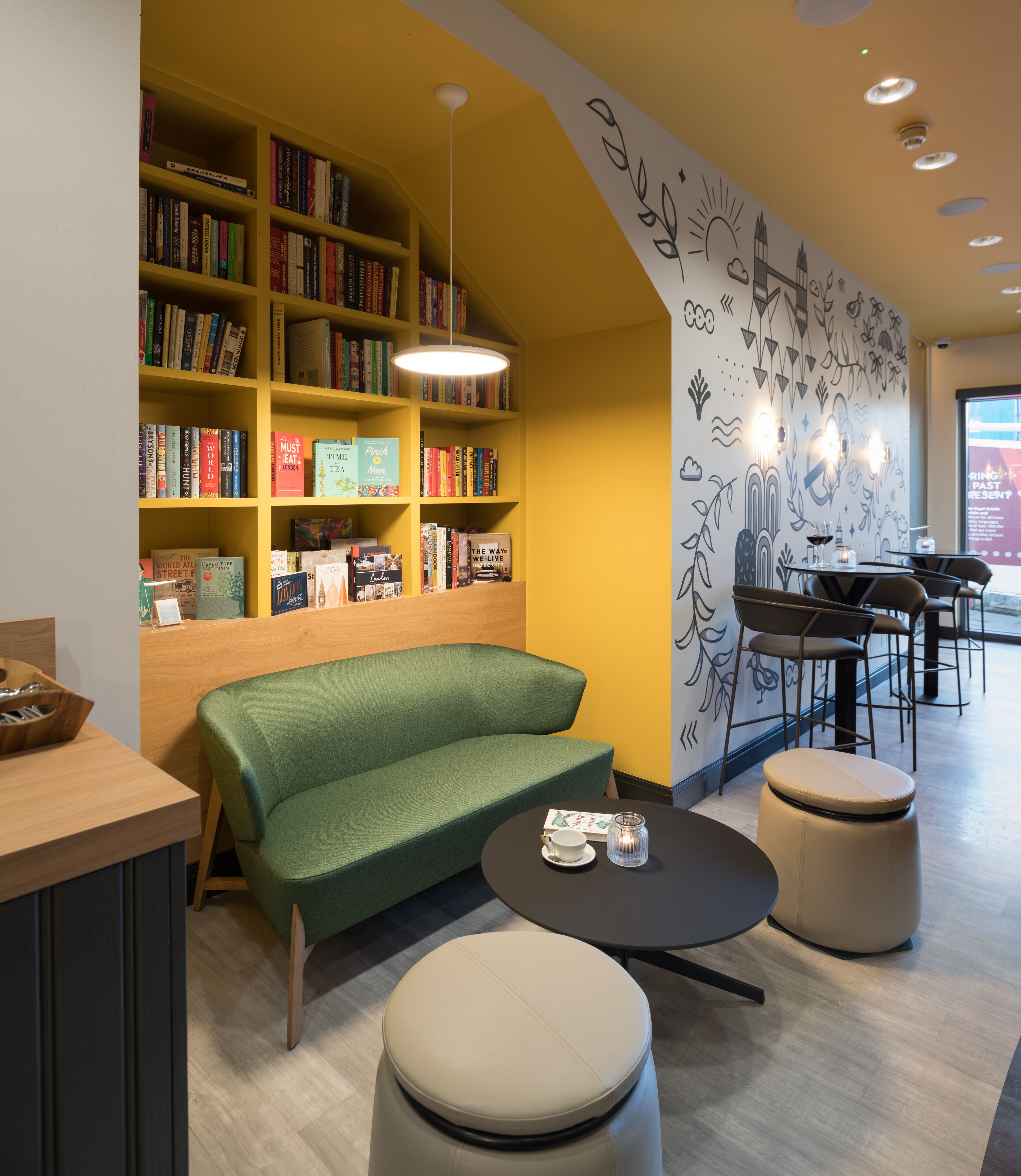 A modern library with bookshelves, a green sofa, and a table with a cup and saucer.