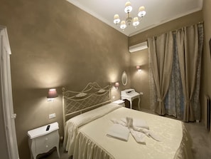 Een hotelkamer met een bed, nachtkastje, lamp en gordijnen.