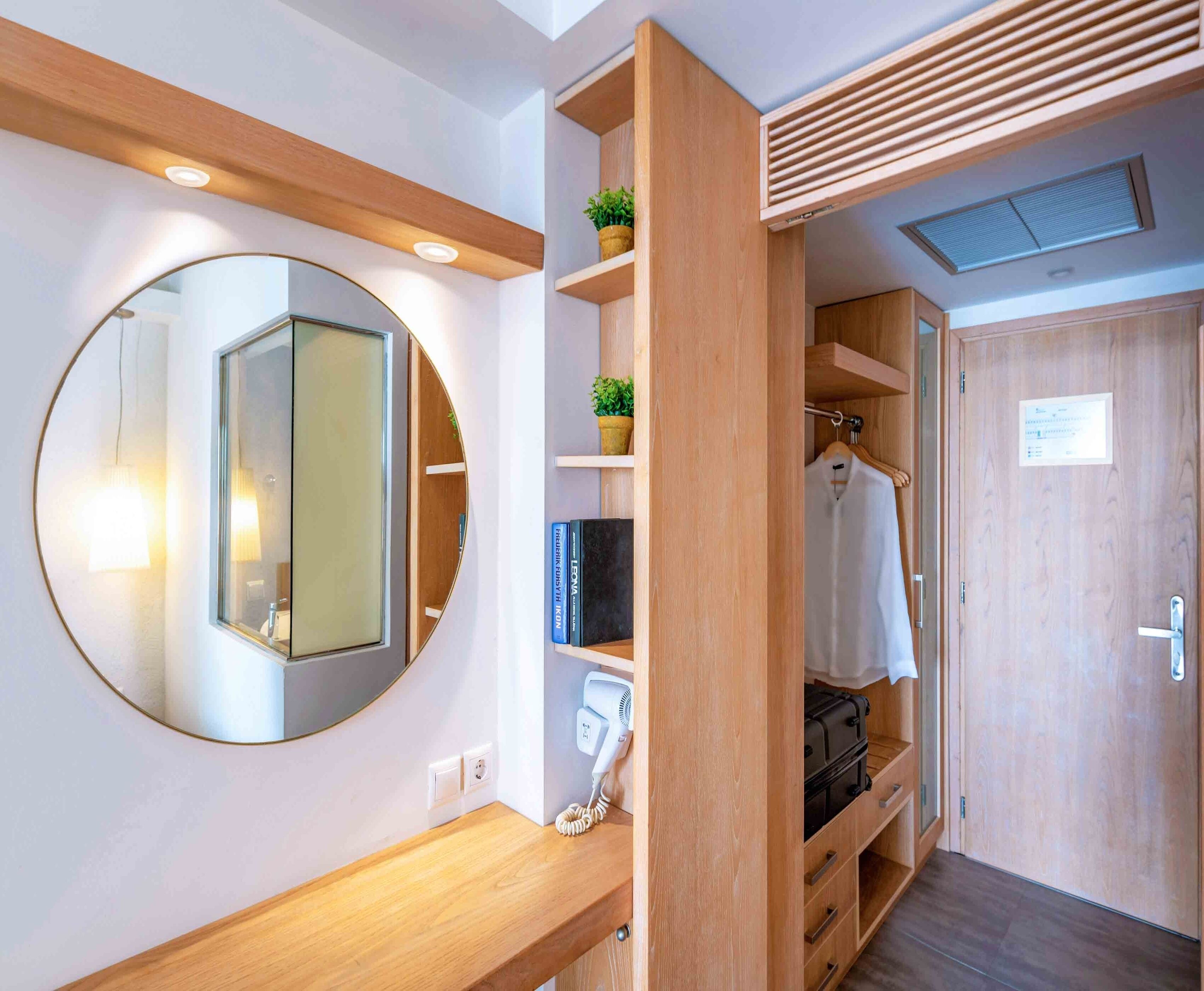 A modern bathroom with a round mirror, wooden vanity, and a towel rack.