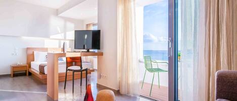 A modern hotel room with a balcony, a television, a dining area, and a bottle of wine.