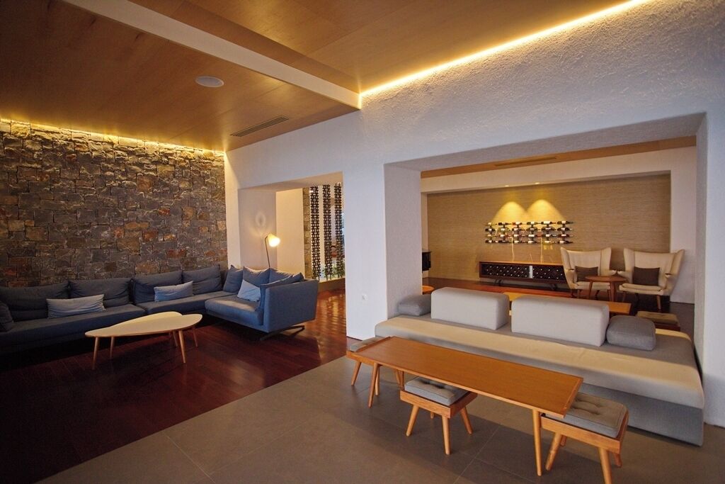 Ein modernes Wohnzimmer mit Steinwand, einem blauen Sofa, einem Holztisch und einem weißen Sofa.
