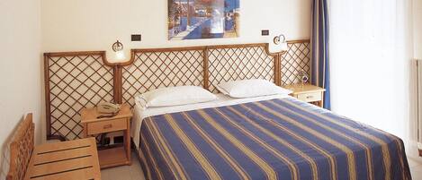 A hotel room with a bed, two bedside tables, a nightstand, a chair, and a painting on the wall.