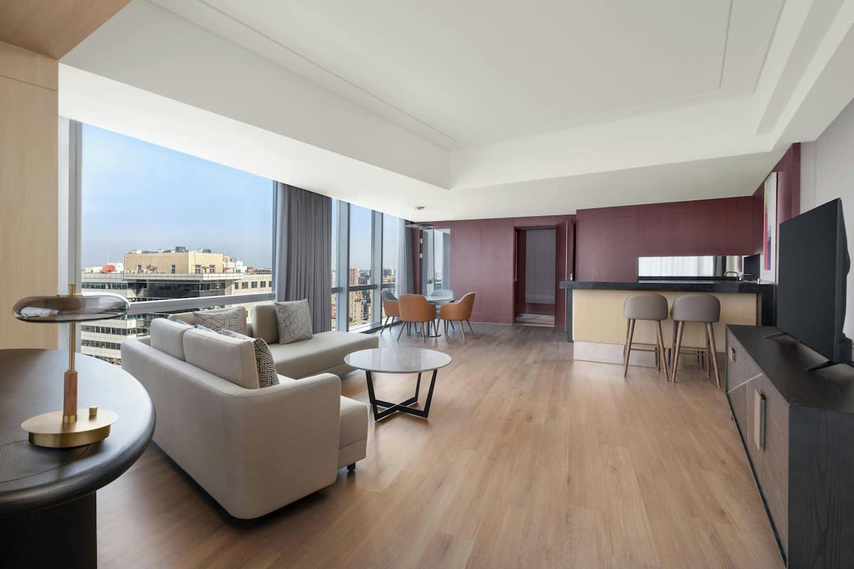 A modern hotel room with a living area, dining space, and a kitchen.