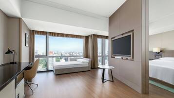 A hotel room with a bed, a desk, a chair, a TV, and a window with a city view.