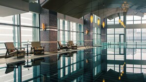 A modern indoor pool area with glass walls, seating, and pendant lighting. - Renaissance Beijing Capital Hotel (Beijing)