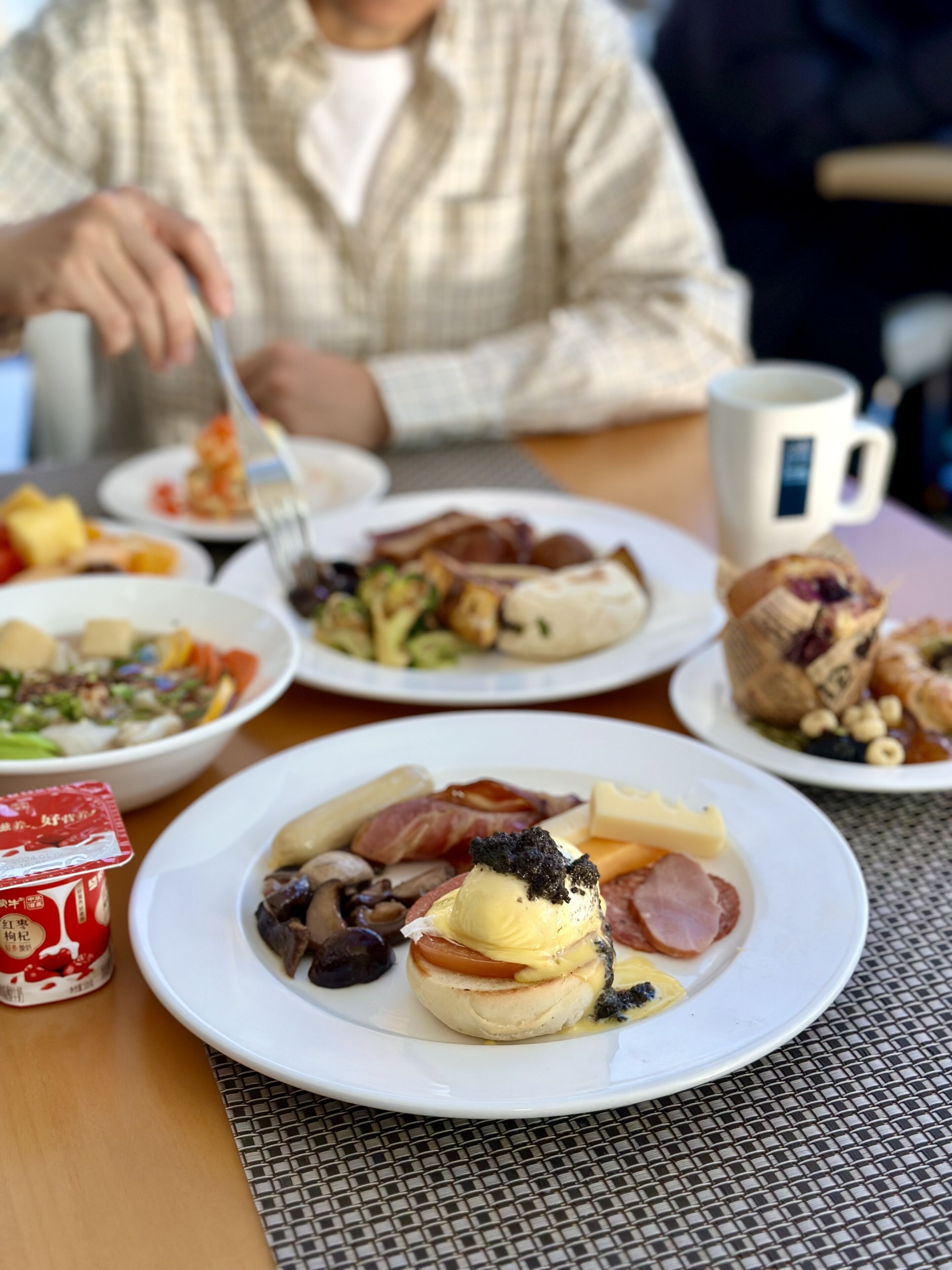 A breakfast setting with various dishes on plates, including eggs, meats, and vegetables.
