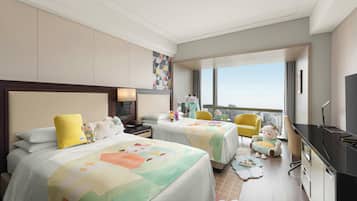 Habitación de hotel con dos camas, un escritorio, una silla, un televisor y un ventanal grande.