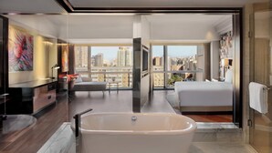 A modern hotel room with a large bathtub, a bed, a desk, and a city view. - Renaissance Beijing Capital Hotel (Beijing)