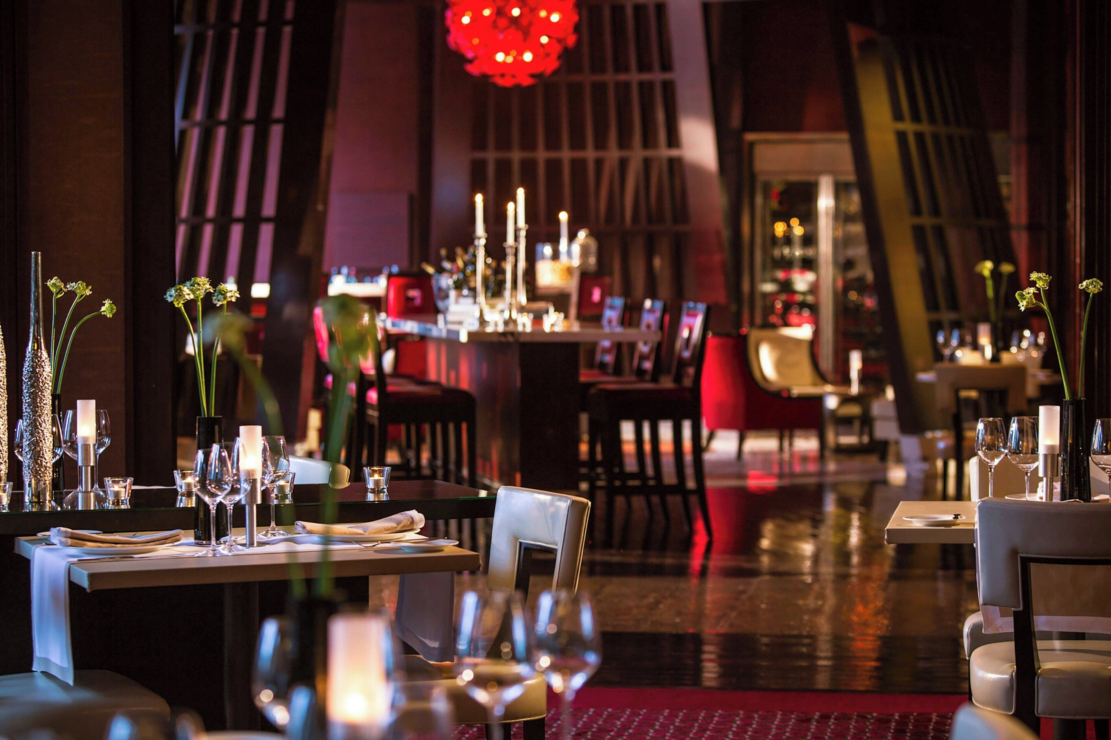 A restaurant with tables set for dining, candles, and floral centerpieces.