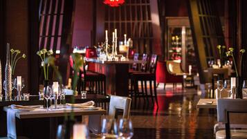 A restaurant with tables set for dining, candles, and floral centerpieces.