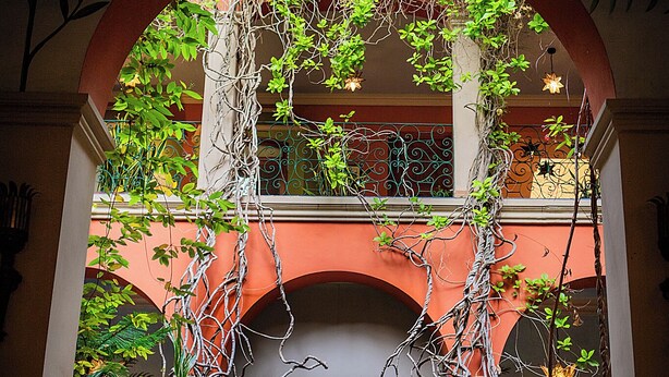 Un atrio interior con una lámpara en forma de estrella, arcos y plantas en macetas.