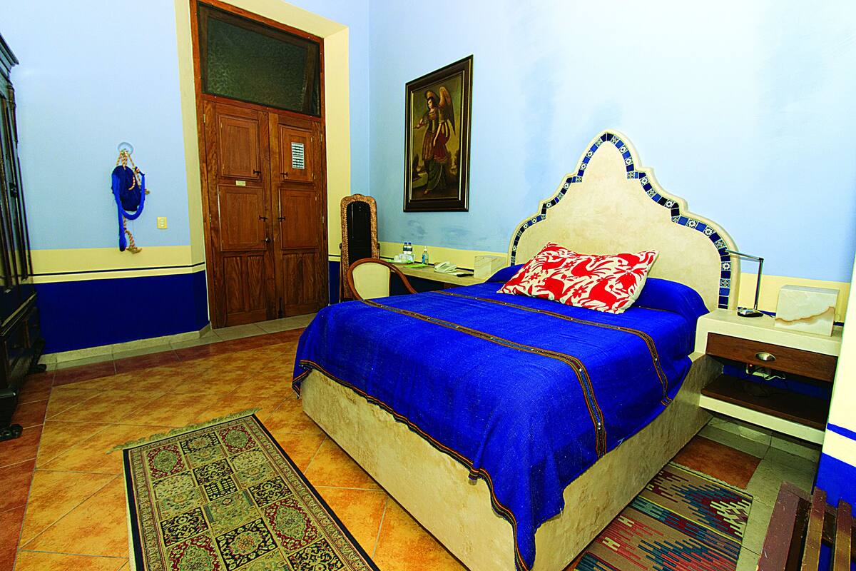 A bedroom with a bed, a desk, a chair, and a wardrobe.