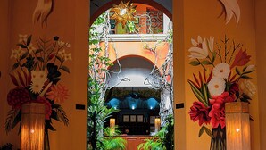 Una entrada con una araña, decoración floral y un letrero que dice "Casa San Angel Hotel Boutique".